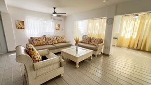 A living room with a sofa set, a coffee table, and a ceiling fan. - 4-bedroom house in the middle of superb Sosúa with WiFi, AC (Sosúa)