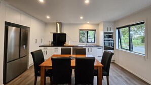 Una cocina moderna con armarios blancos, electrodomésticos de acero inoxidable y un comedor con mesa y sillas de madera.