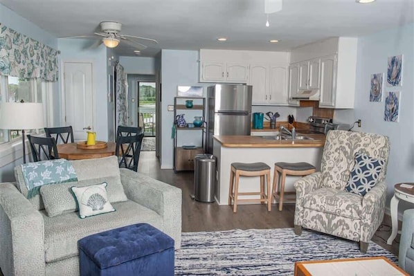 A modern kitchen with white cabinets, a stainless steel refrigerator, and a wooden island.