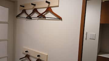 Una habitación con perchas de madera en un perchero de pared y una puerta con interruptor de luz.