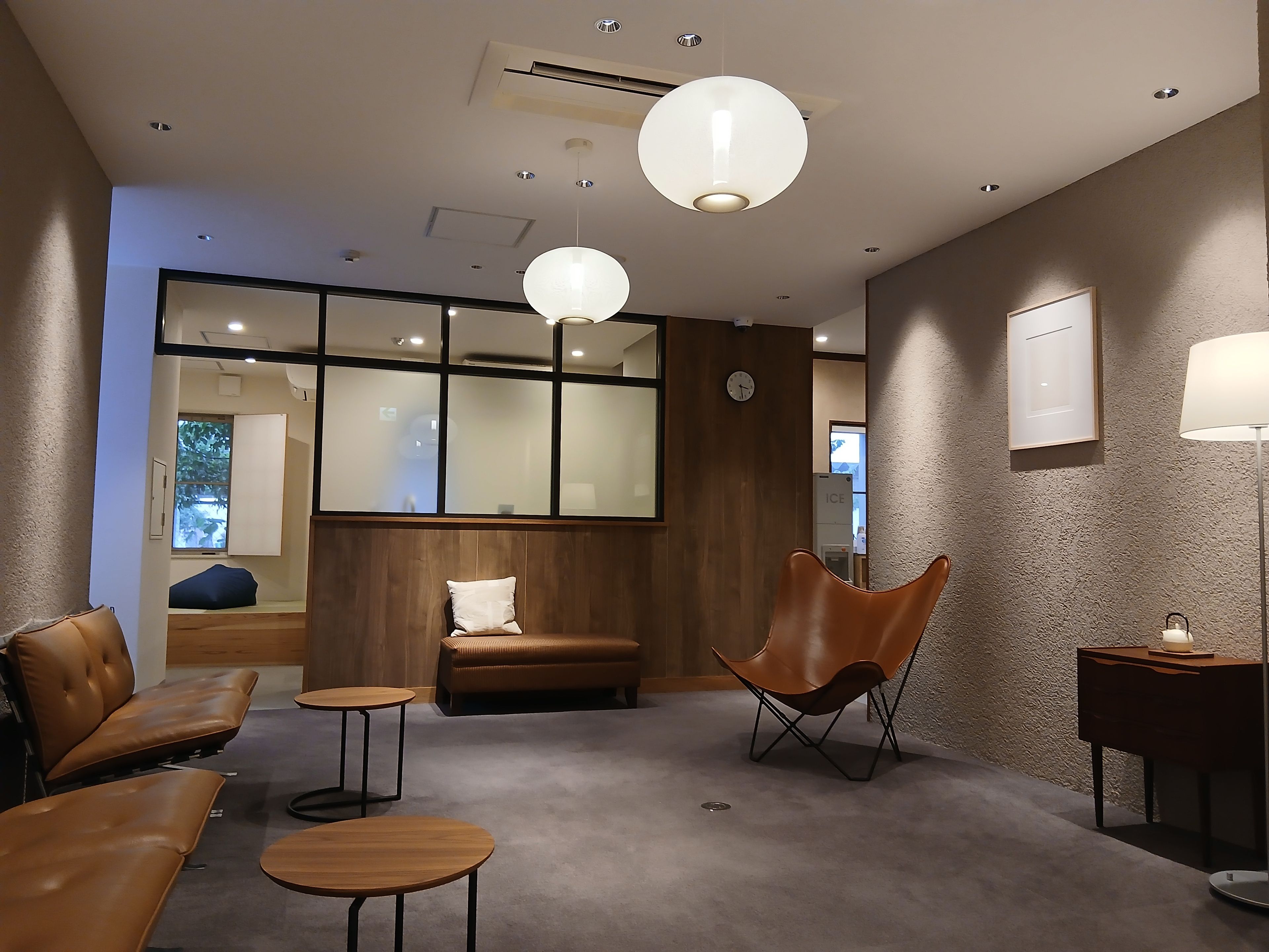 A modern interior with seating arrangements, a clock, and a large window.