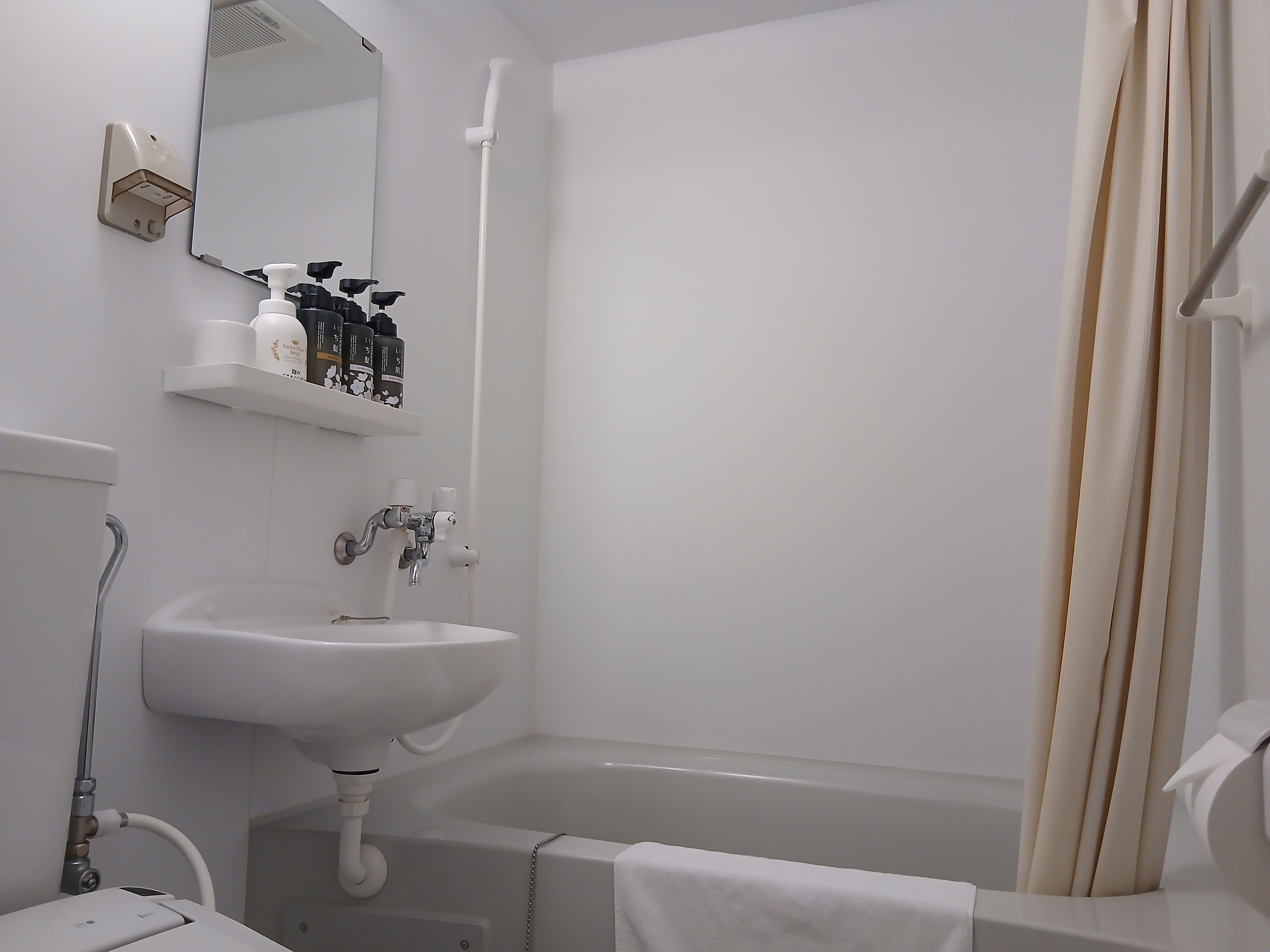 A bathroom with a sink, mirror, and shower area.