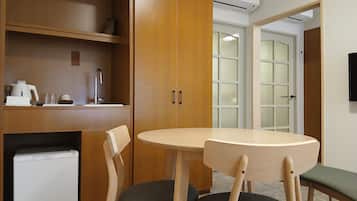 A compact room with a kitchenette, a dining table with chairs, and a built-in refrigerator.