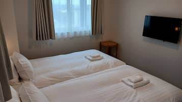 A hotel room with two beds, a TV on the wall, and a small wooden table.