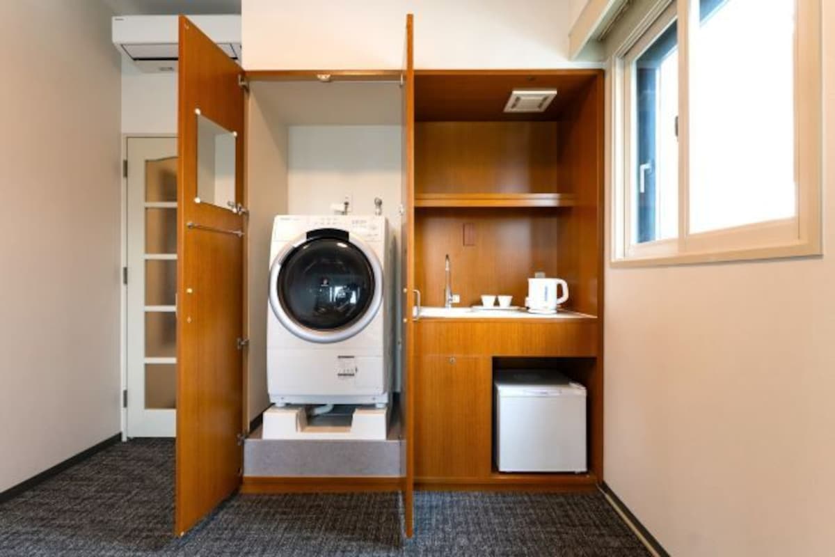 A compact laundry room with a washing machine, a small sink, and a cabinet.