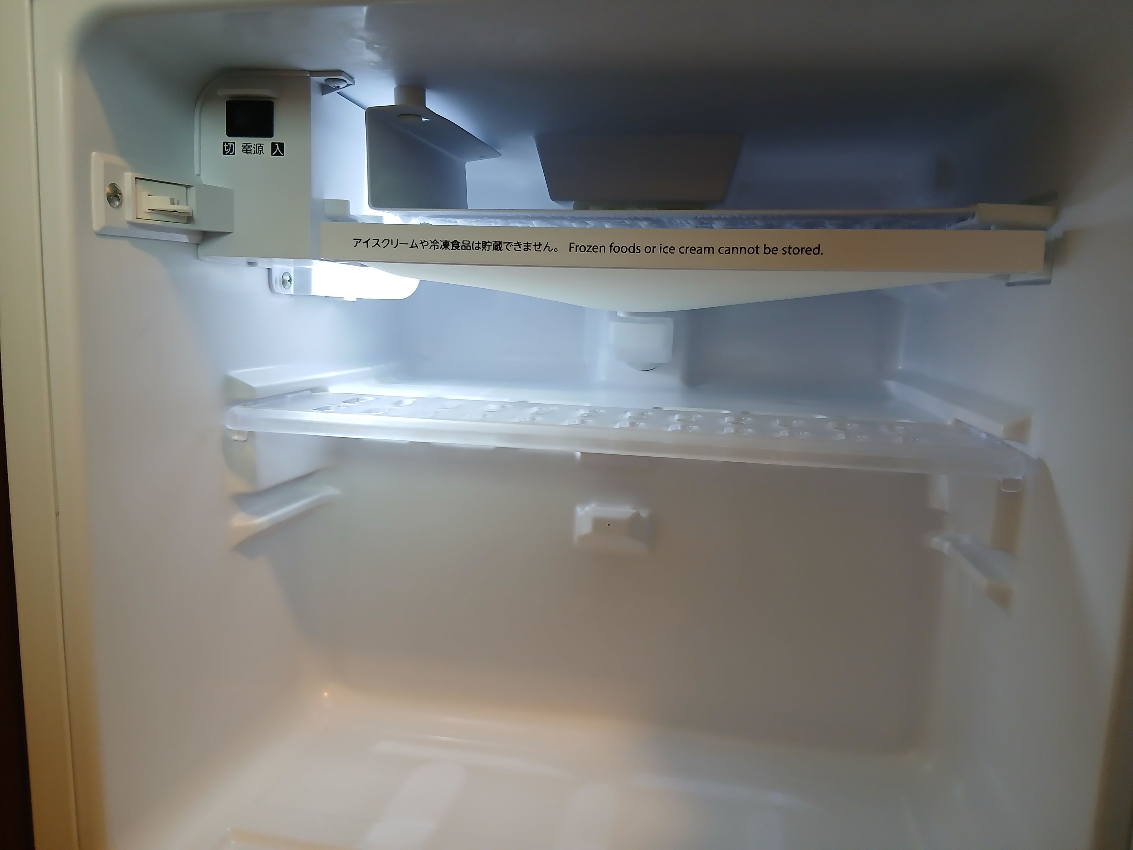 Frigorifero vuoto con pannello di controllo ed etichetta di avvertimento.