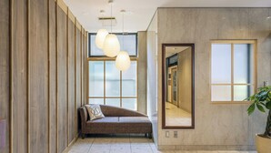 A modern hotel lobby with a sofa, large windows, and a mirror.