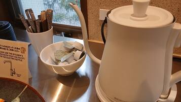 A kitchen area with a white electric kettle, a bowl with tea bags, and a sign indicating the use of filtered water for the kettle.
