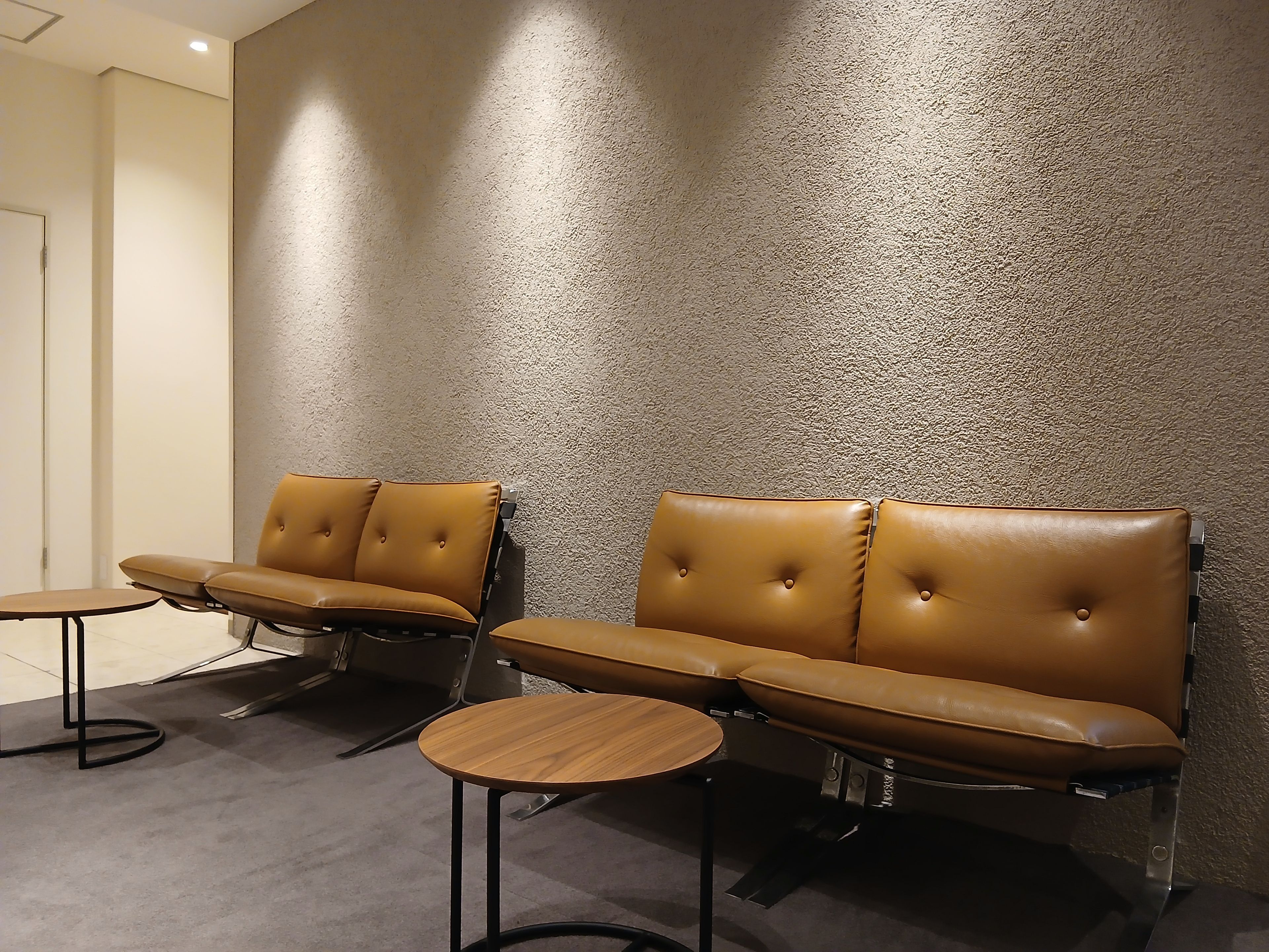 A seating area with two sofas and a small round table, against a textured wall.