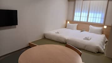 Quarto de hotel com uma cama, televisão e uma mesa redonda.