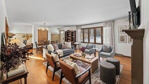 A spacious living room with a sofa, armchairs, a coffee table, and a dining area with a table and chairs. - Remodeled Home on Wooded Nagawicka Lake Channel (Delafield)