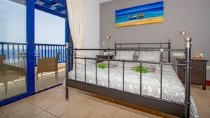 A bedroom with a bed, a painting, and a balcony with wicker chairs. - Casa Yaiza - Three Bedroom Villa, Sleeps 6 (Puerto Calero)