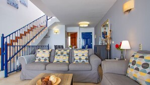 A living room with a grey sofa, a wooden coffee table, and a blue staircase. - Casa Yaiza - Three Bedroom Villa, Sleeps 6 (Puerto Calero)