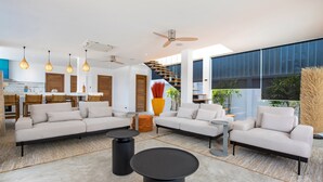 A spacious living area with a large sofa set, two black coffee tables, and hanging pendant lights. A large vase with red flowers is centrally placed. - Boutique 5BR Oxygen Pool Villa Samakki 5 (Rawai)