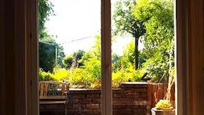 Vista a través de una ventana con un muro de ladrillo y follaje en el exterior.