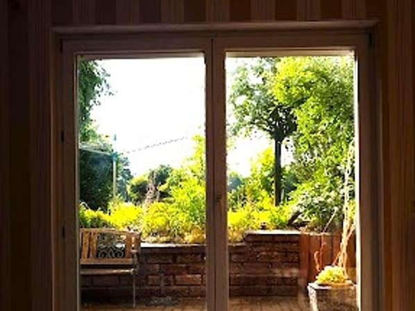A view through a window with a brick wall and greenery outside.