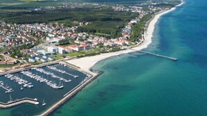 Vista aérea de un pueblo costero con puerto deportivo, playa y zona residencial.