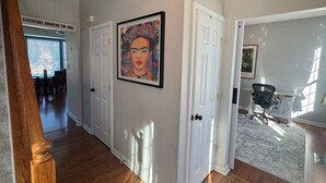 A hallway with wooden floors, white doors, and a framed artwork on the wall. - Colonial Playland - 5BD, Private Yard, Game Room (Manassas)