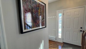 A hallway with a framed abstract painting, a white door, and a wooden floor. - Colonial Playland - 5BD, Private Yard, Game Room (Manassas)