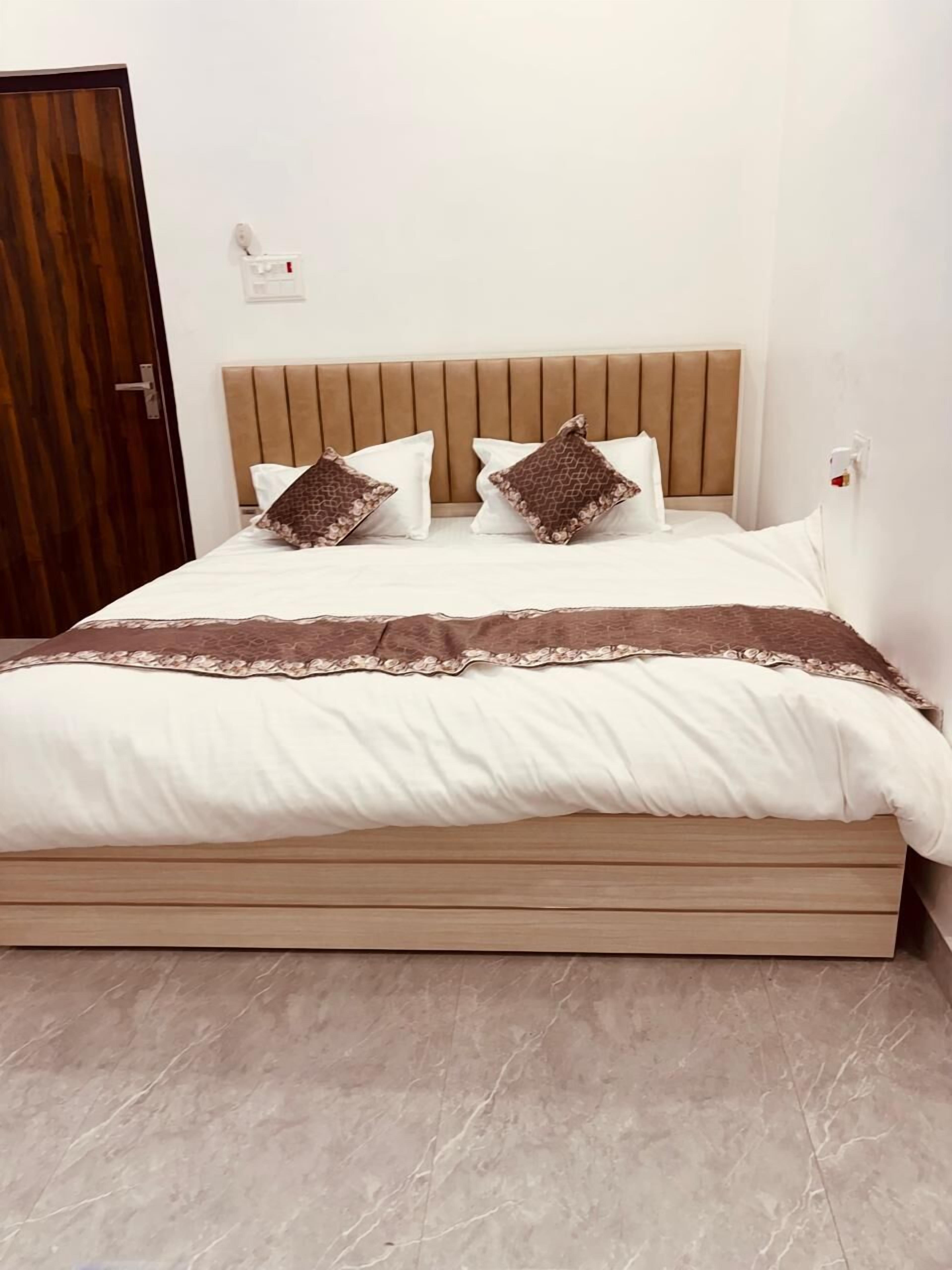 A neatly made bed with a wooden headboard, white bedding, and two decorative pillows.
