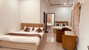 Ein modernes Hotelzimmer mit einem großen Bett, einem kleineren Bett, einer Couch und einem Sessel.