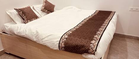 A bed with a wooden frame, white bedding, and decorative pillows.