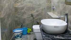 Ein Badezimmer mit Marmorwand, einem weißen Waschbecken, einer Toilette und einer Dusche.