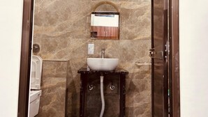 Ein Badezimmer mit Marmorwand, einem weißen Waschbecken, einem Spiegel und einem Handtuchhalter.
