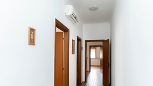 A narrow hallway with wooden doors and a ceiling-mounted air conditioner.