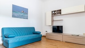 A modern living room with a blue sofa, a flat-screen TV, and a wooden cabinet.