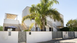 Un edificio moderno con fachada blanca, base de piedra y una escalera que conduce a un nivel superior.