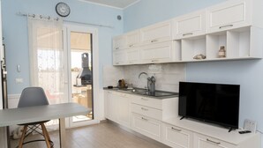 Una cocina moderna con armarios blancos, horno empotrado y televisor de pantalla plana.