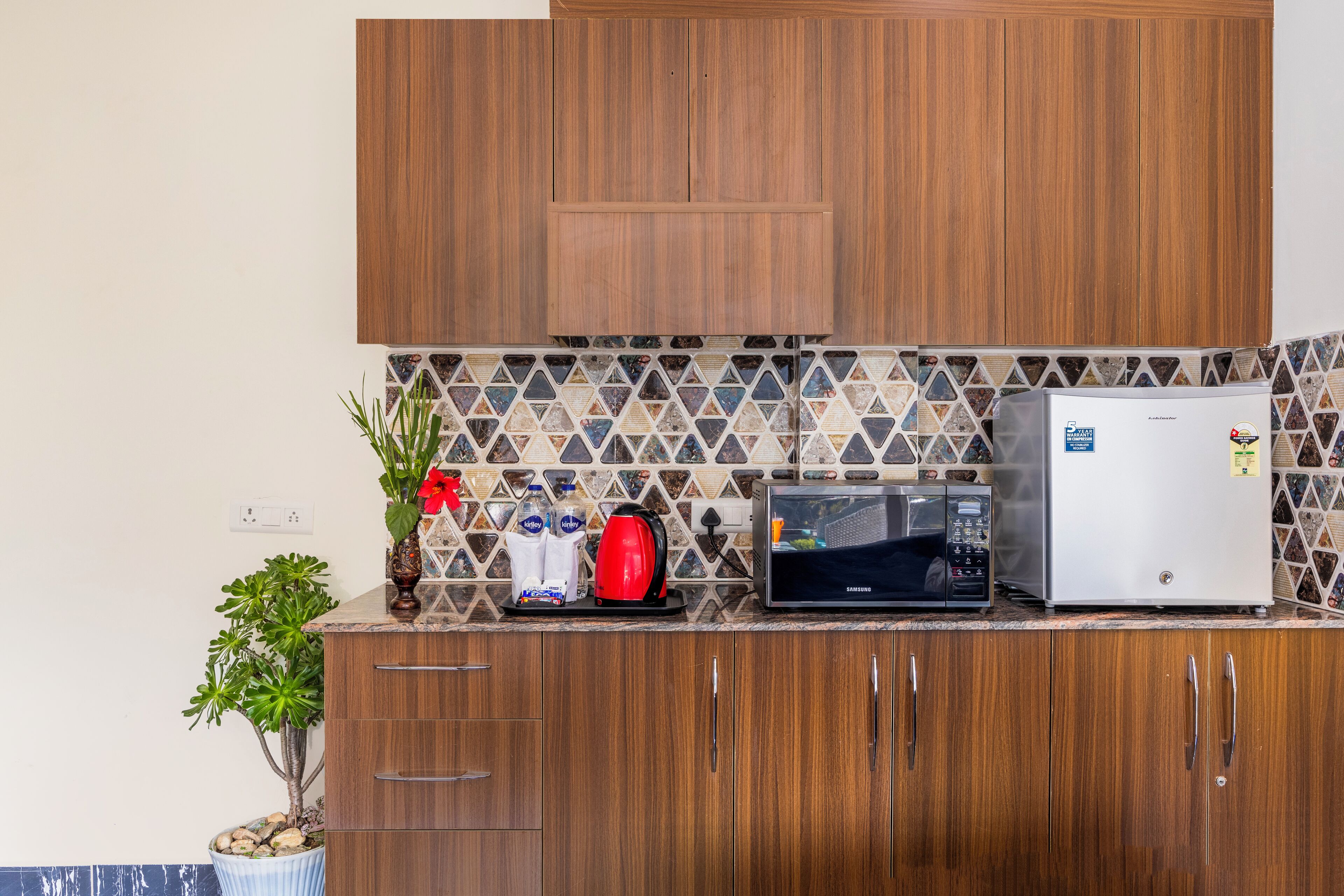 Una cocina con armarios de madera, microondas, refrigerador y salpicadero de azulejos.