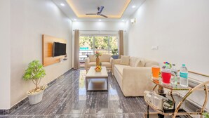 A modern living room with a sofa, coffee table, and a small side table with drinks and a water bottle.