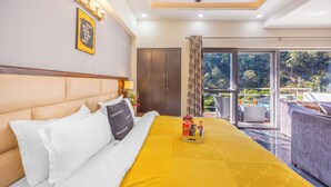 A hotel room with a bed, a wardrobe, a balcony with a view, and a ceiling fan.