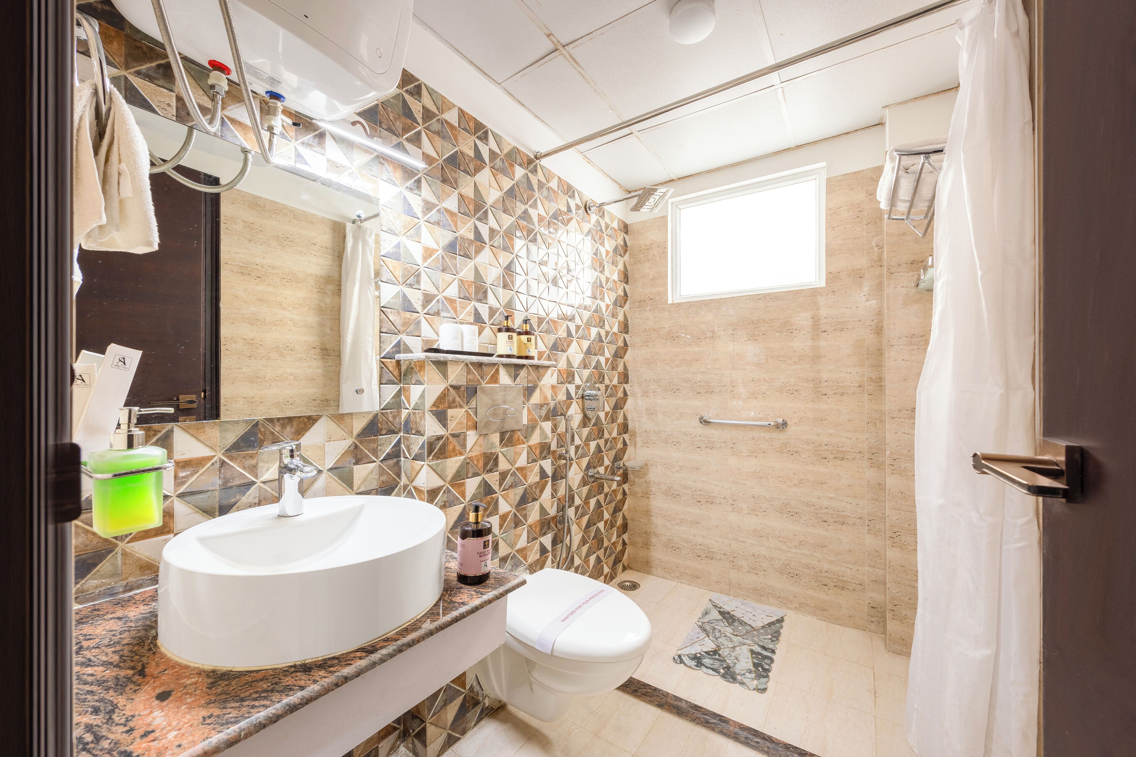 Casa de banho com lavatório branco, sanita, chuveiro e parede revestida a azulejos.