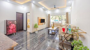 A modern living room with a marble floor, a sofa set, a coffee table, a TV mounted on the wall, and a ceiling fan.