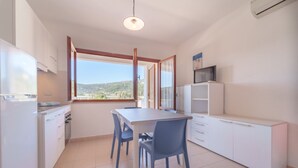 A compact kitchen with a dining table, chairs, and a view of the outdoors.