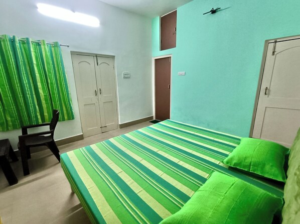 A room with a bed, a chair, and two doors.
