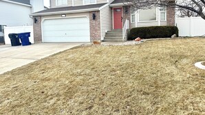 A residential house with a garage, a brick facade, and a front yard with a trimmed bush.