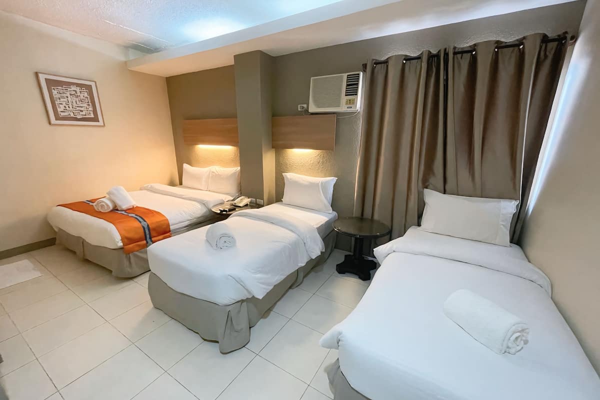 Habitación de hotel con dos camas, una mesita de noche, un equipo de aire acondicionado y un teléfono instalado en la pared.