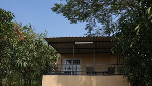 Un edificio con techo plano, un balcón con barandillas y una puerta con ventanas.