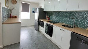 A modern kitchen with white cabinets, a wooden countertop, a built-in oven, and a dishwasher.
