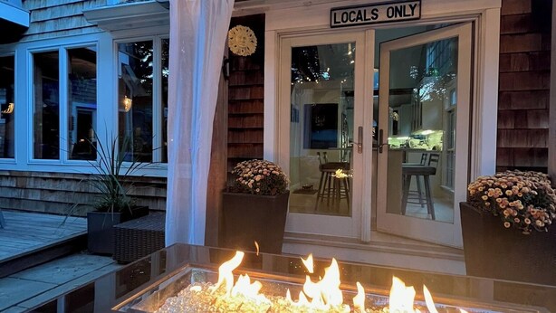 An outdoor patio with a glass enclosure, a fire feature, and a sign reading "Locals Only".