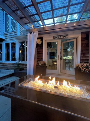 An outdoor patio with a glass enclosure, a fire feature, and a sign reading "Locals Only".