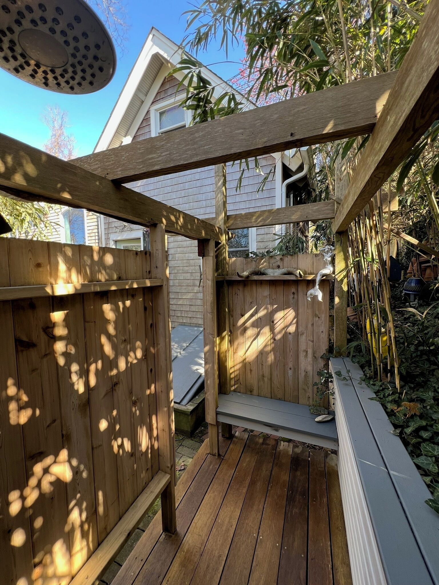 Een houten terras met een pergola, een klein bankje en een waterpartij.