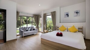 A modern hotel room with a large bed, a sofa, and a view of the outdoors.