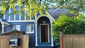 A house with a blue exterior, a wooden gate, and a small front yard with steps leading to the door.