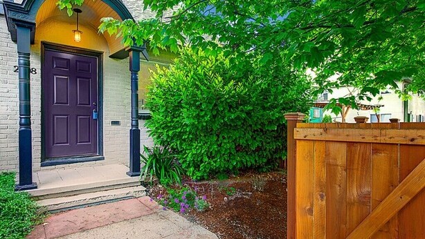 A house with a purple door, a brick pathway, and a wooden fence.