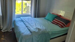 A bedroom with a bed, curtains, and a window.